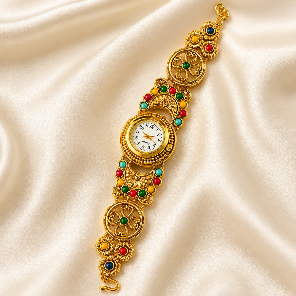 An ornate gold watch bracelet with colorful gemstone accents, displayed on a draped cream satin fabric background.