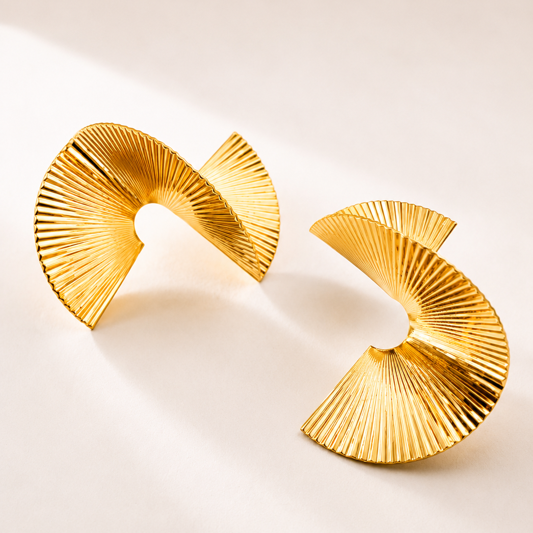 Pair of gold tone earrings on a light beige background