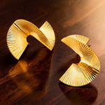 Gold tone earrings on a wooden surface
