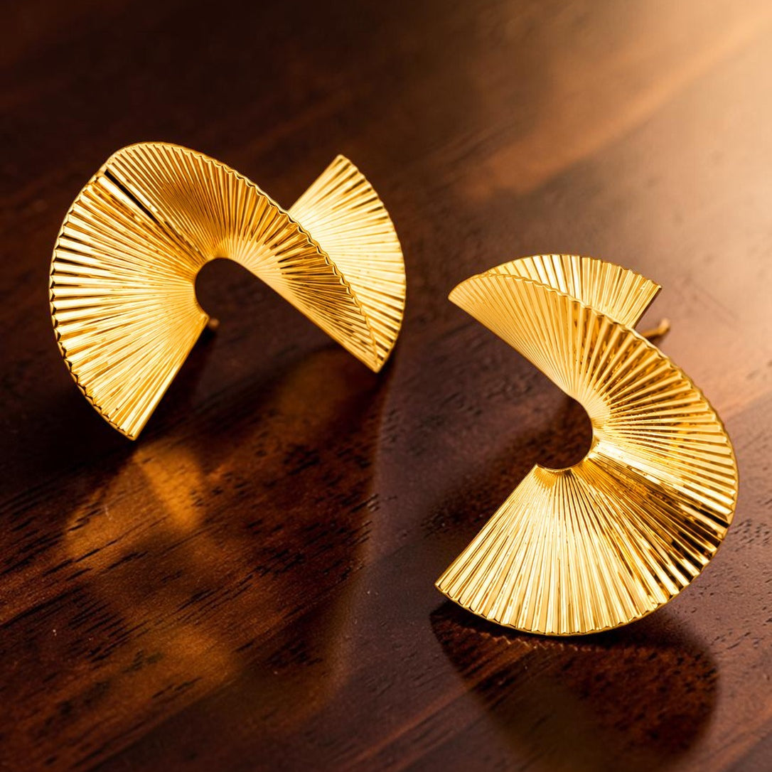 Gold tone earrings on a wooden surface