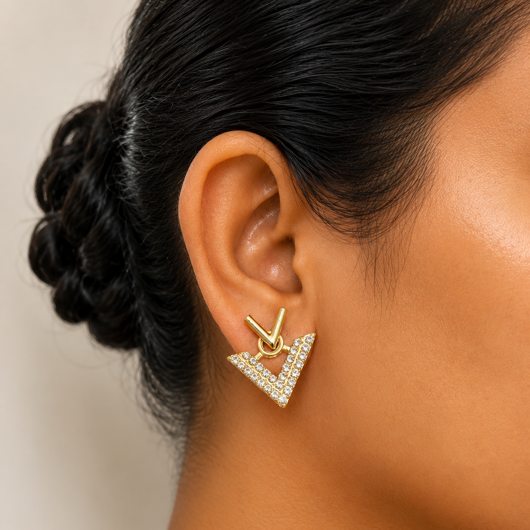 Close-up of an ear wearing a golden  earring against a neutral background