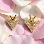Golden V-shaped earrings with diamond accents on pink flower petals