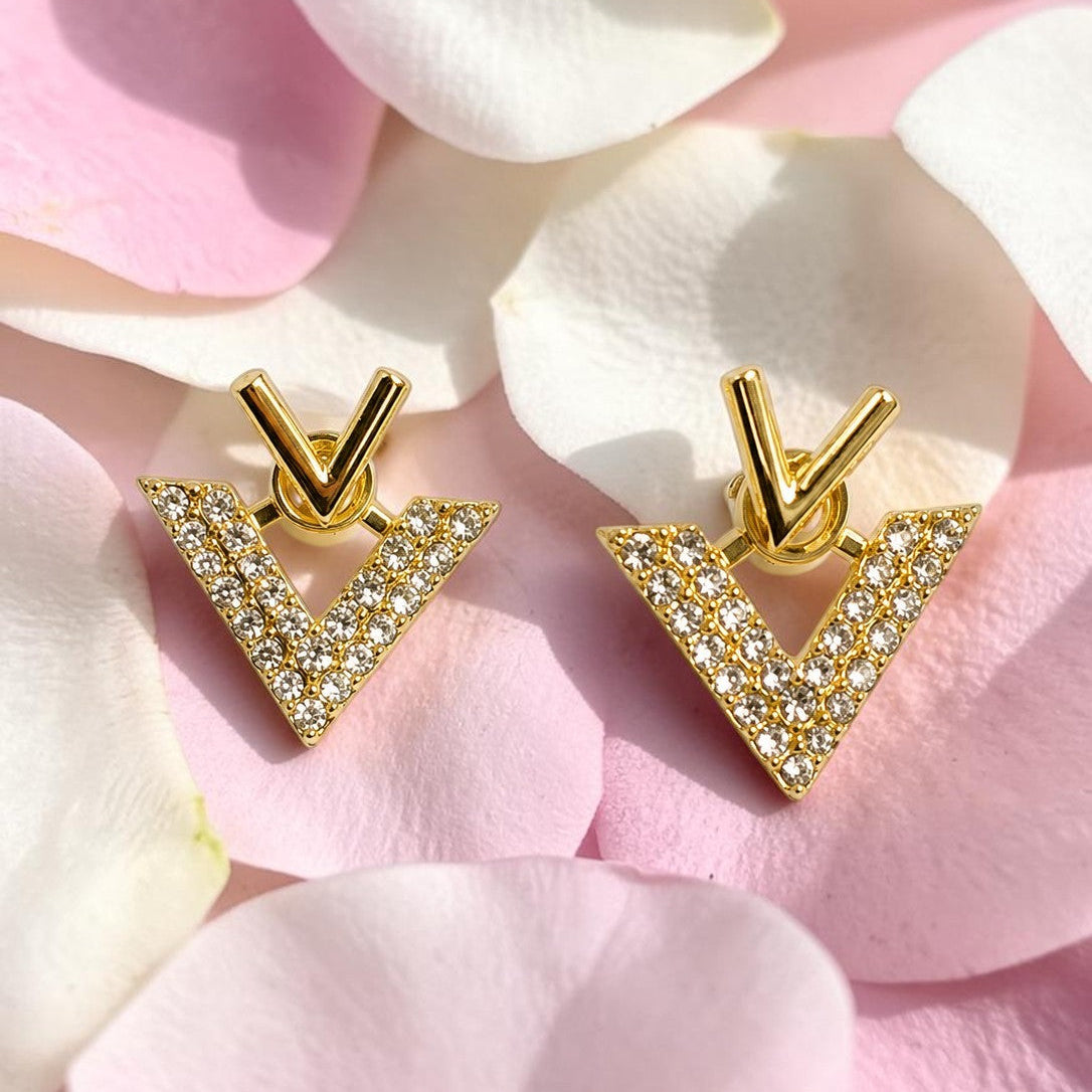 Golden V-shaped earrings with diamond accents on pink flower petals