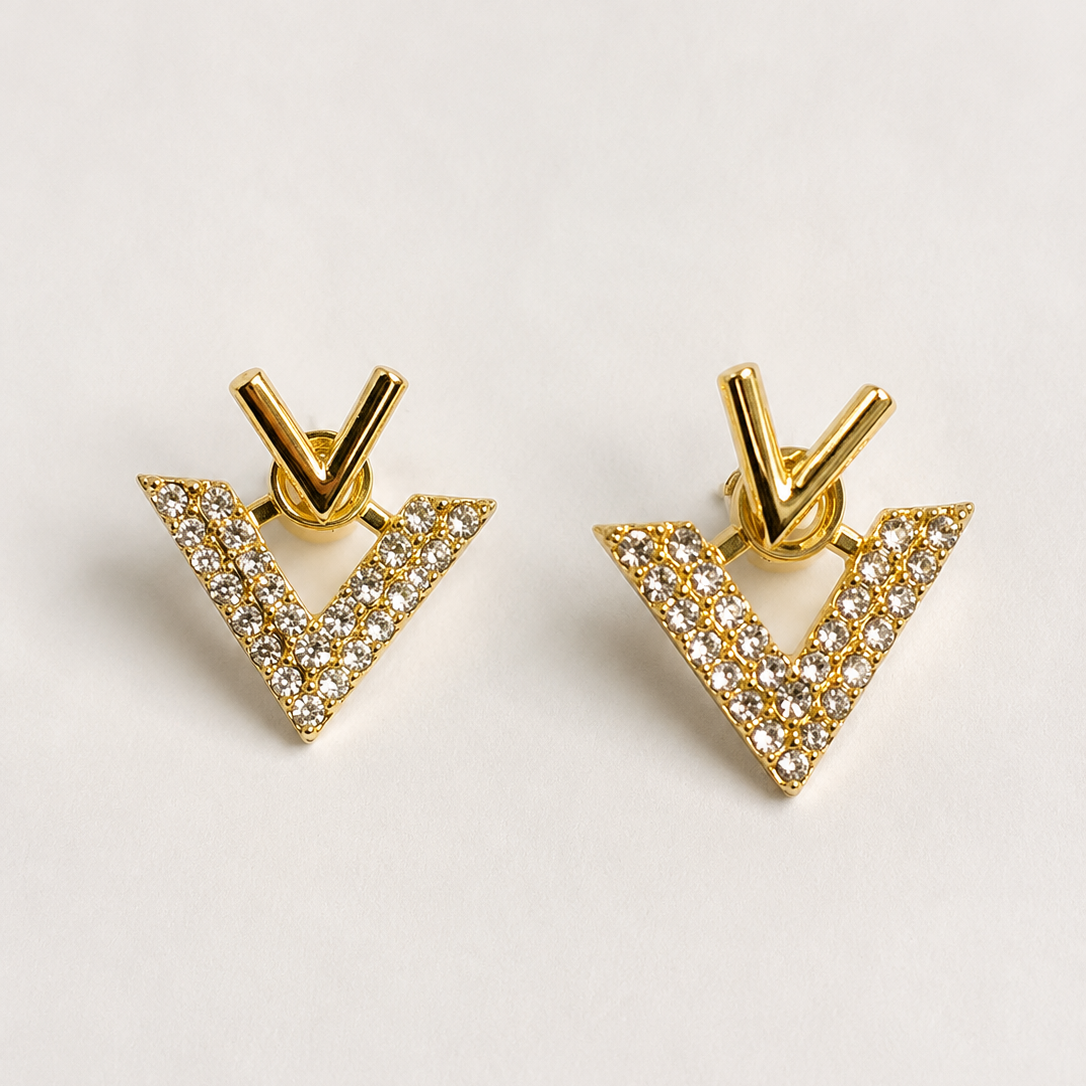 Golden triangle earrings with clear stones on a light gray background