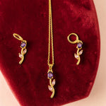 Gold tone necklace with purple stones on a red velvet cushion