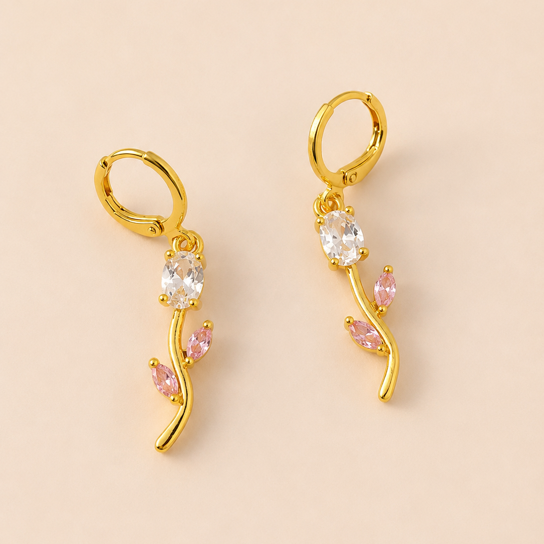 Gold  tone earrings with gemstones on a beige background