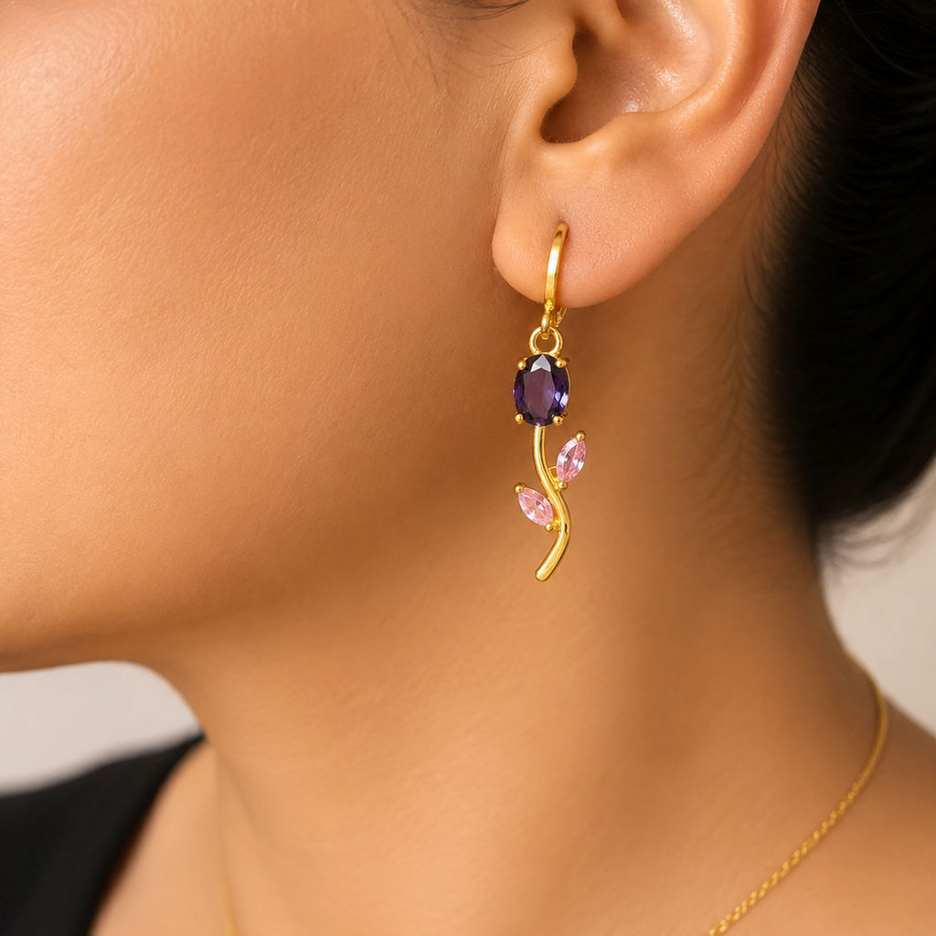 Gold tone earring with purple gemstone worn by a person