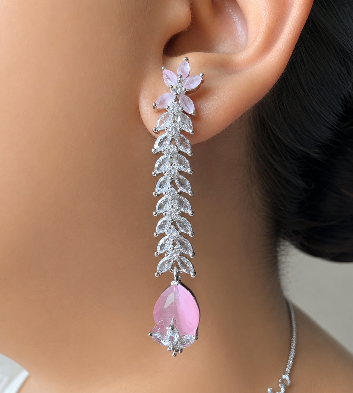 Earring with pink gemstone and silver leaves worn on an ear