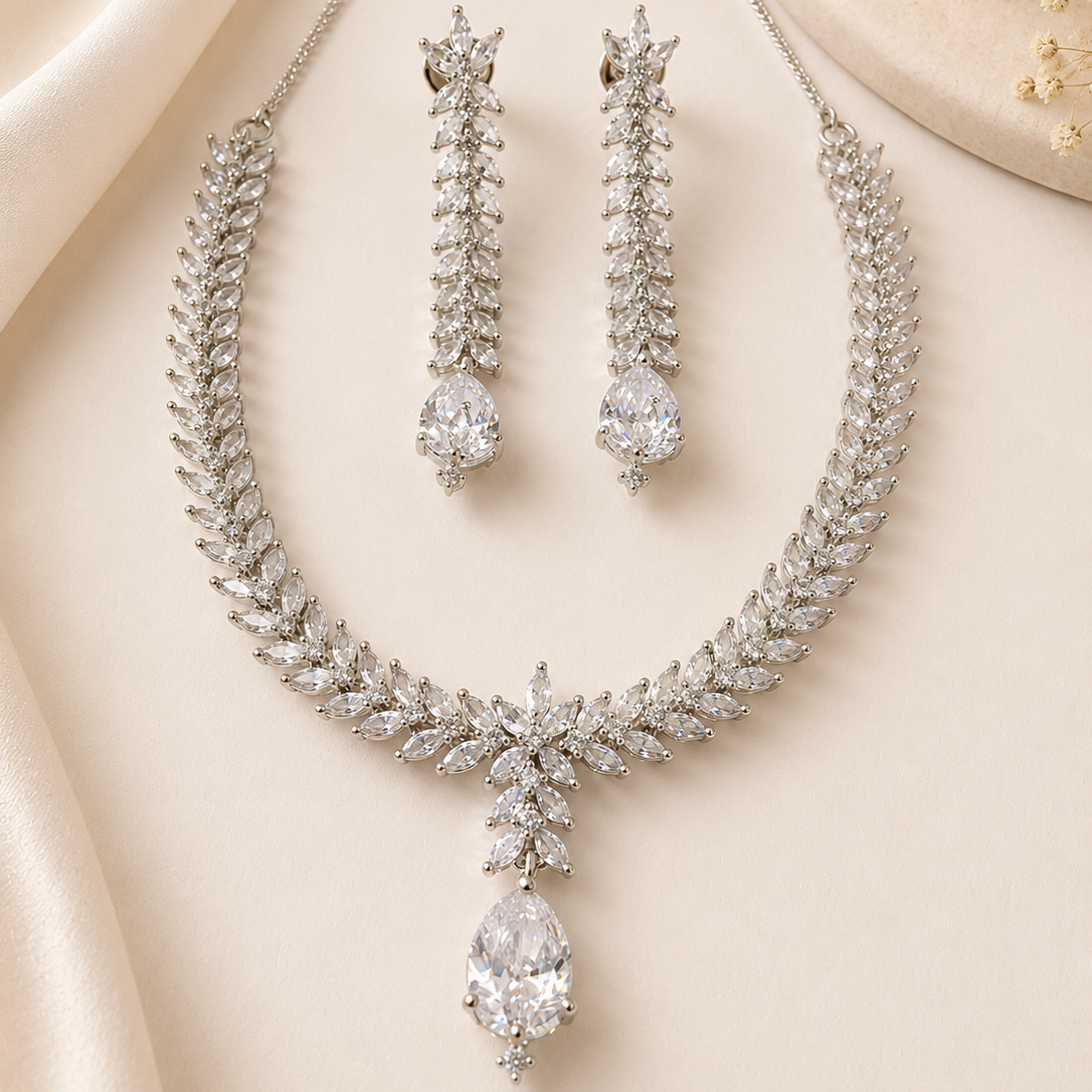 Silver necklace and earrings set on a beige fabric background