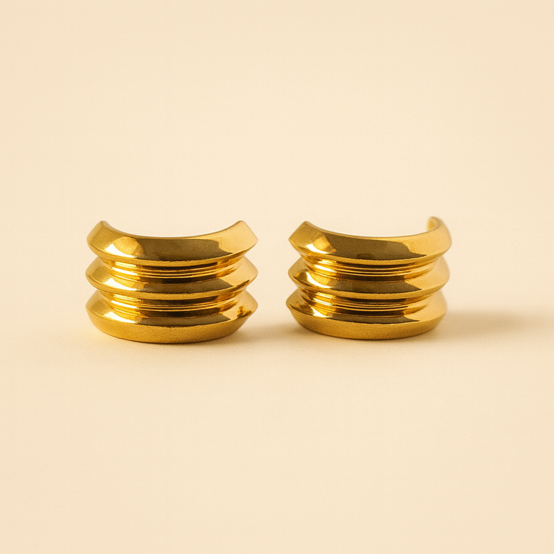 Pair of gold tone hoop earrings on a beige background