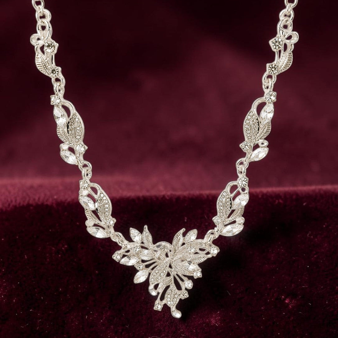 Silver necklace with floral design on a maroon fabric background