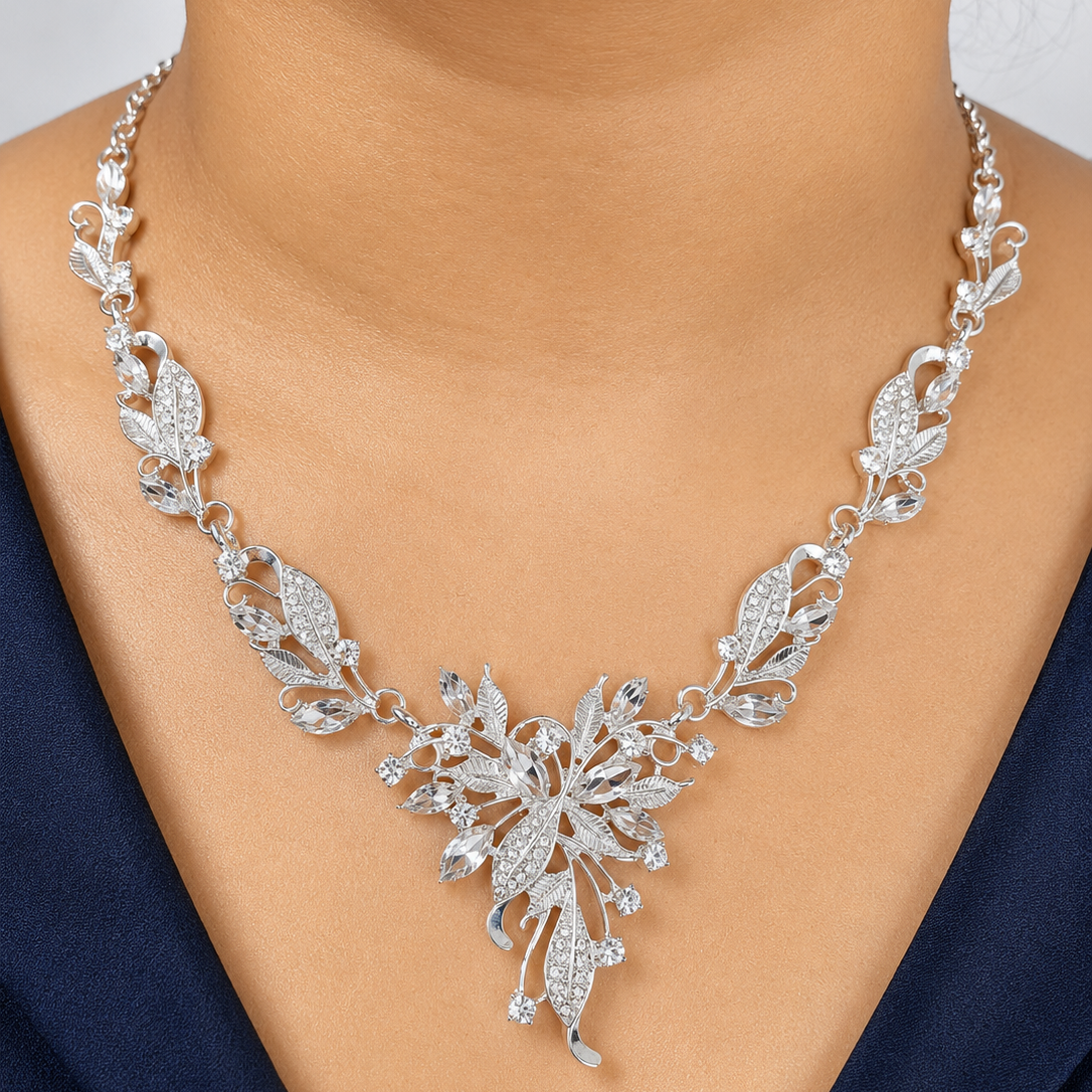 Silver necklace with floral design worn by a model against a neutral background