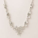 Silver necklace with floral design on a light pink background
