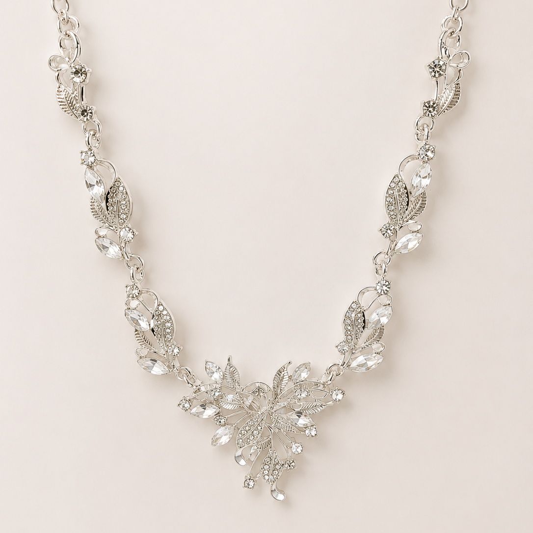 Silver necklace with floral design on a light pink background