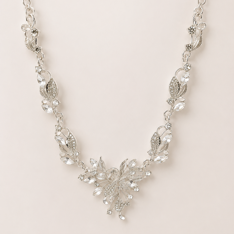 Silver necklace with floral design on a light pink background