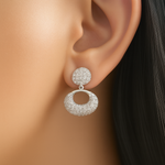 Silver earrings with circular design worn by a person with black hair.