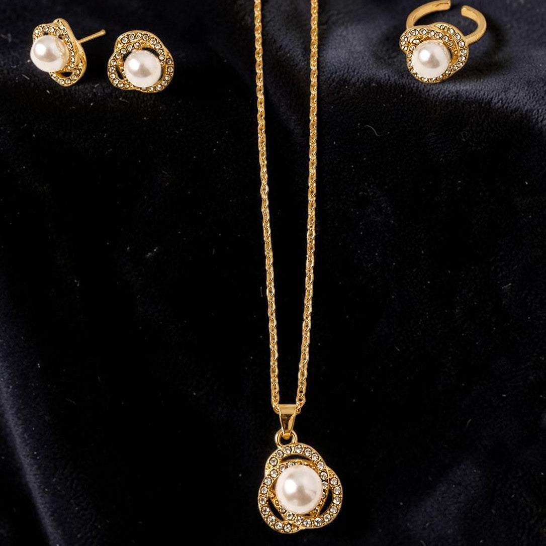 Gold tone necklace with pearl pendant and matching earrings on a black background