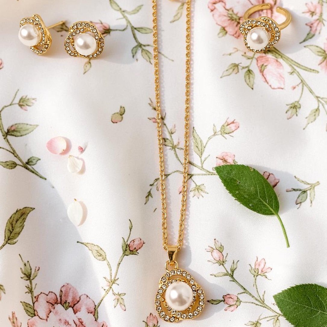 Gold tone necklace with a pearl pendant and matching earrings on a floral background