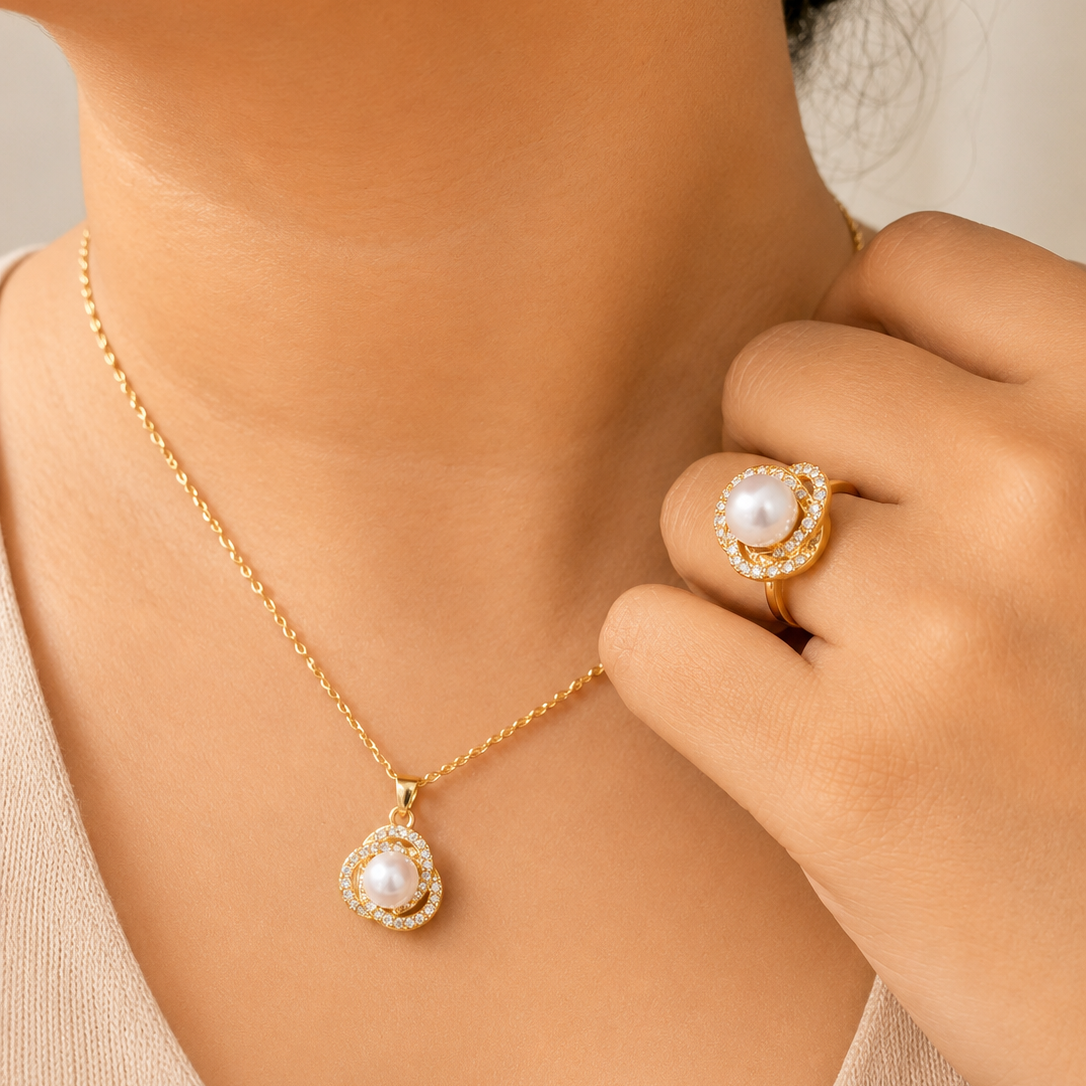 Gold tone necklace and ring with pearl accents on a neutral background