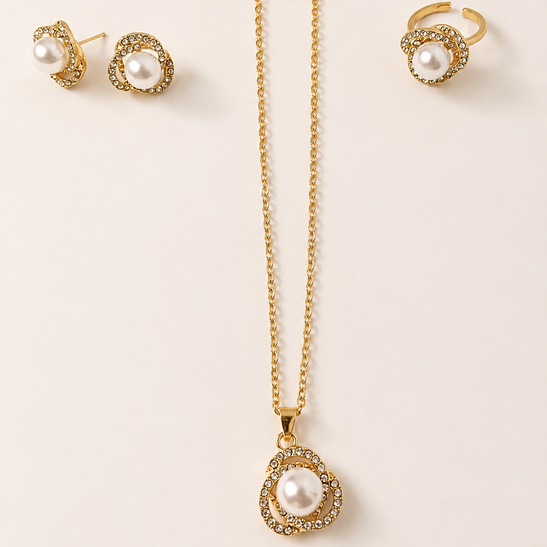 Gold tone necklace with pearl pendant and matching earrings on a beige background