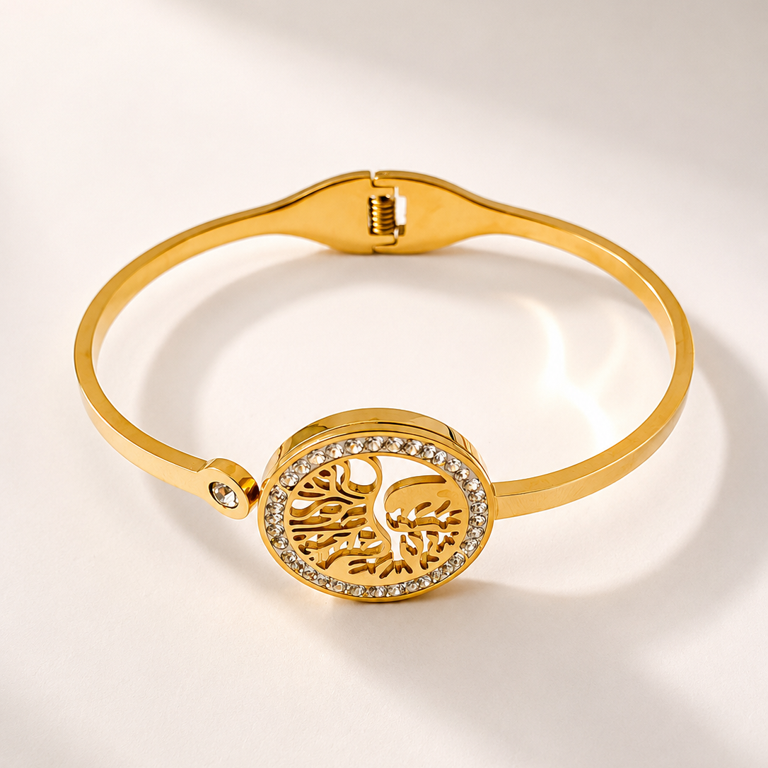Gold tone bracelet with a tree of life design on a light background