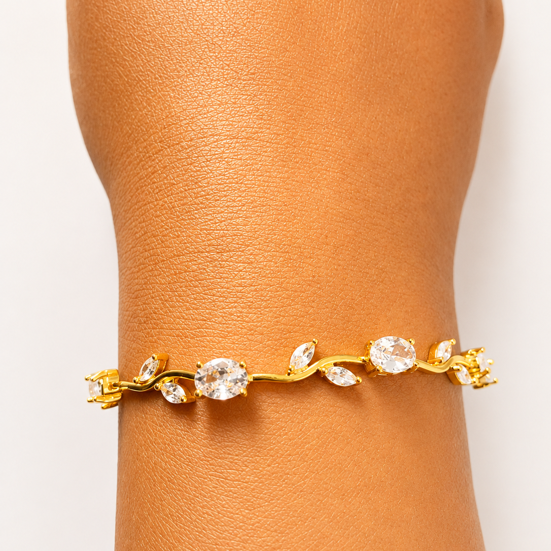 Gold tone bracelet with clear stones on a wrist against a light background