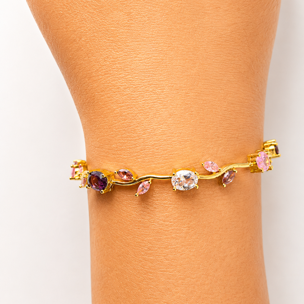 Gold tone bracelet with colorful gemstones on a person's wrist against a white background
