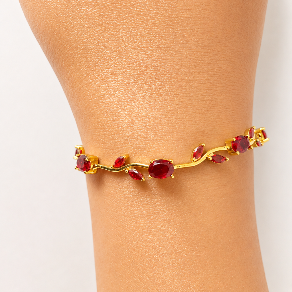 Gold tone bracelet with red gemstones on a person's wrist against a white background