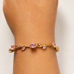 Gold tone bracelet with pink gemstones on a wrist against a light background