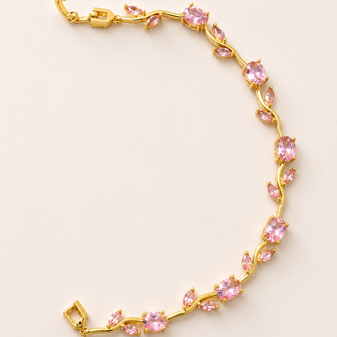 Gold tone bracelet with pink gemstones on a light beige background