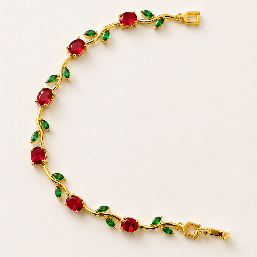 Gold tone bracelet with red and green gemstones on a light beige background