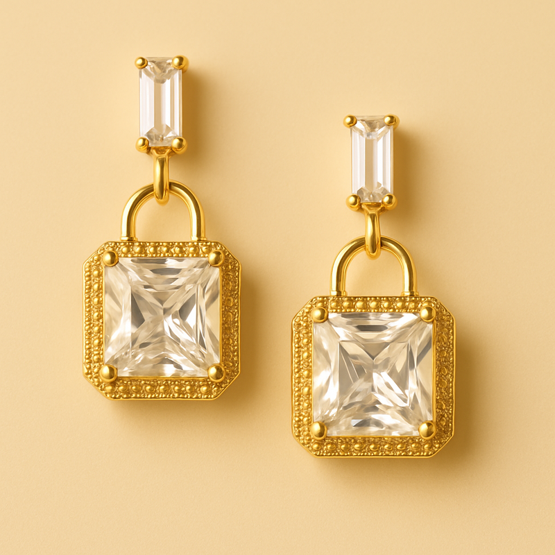 Gold tone earrings with clear gemstones on a beige background
