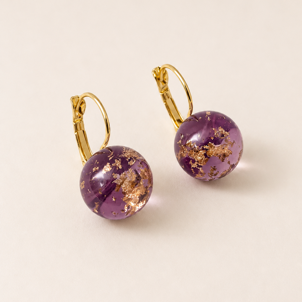 Purple earrings with gold accents on a beige background