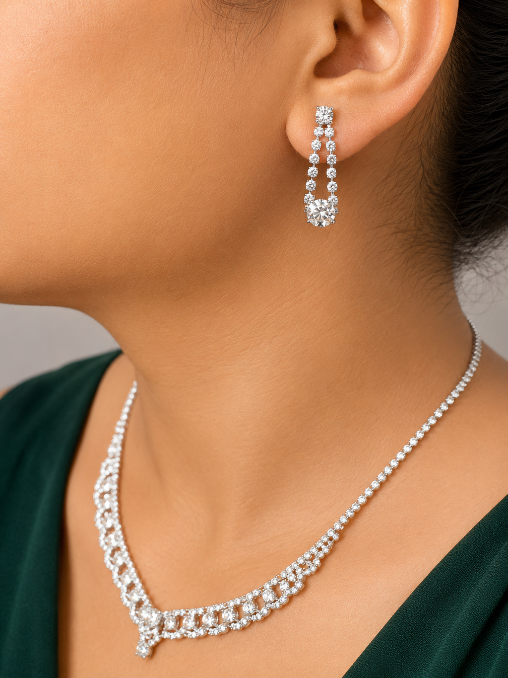 Close-up of a person wearing a american diamond necklace and earrings on a neutral background