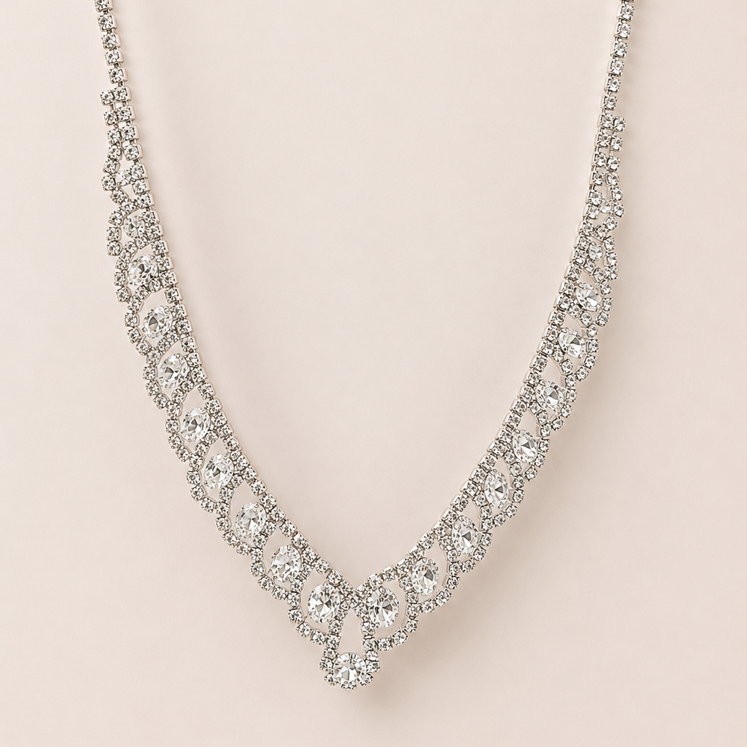 Silver necklace with clear stones on a light pink background