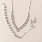 Silver jewelry set with necklace, bracelet, and earrings on a beige background
