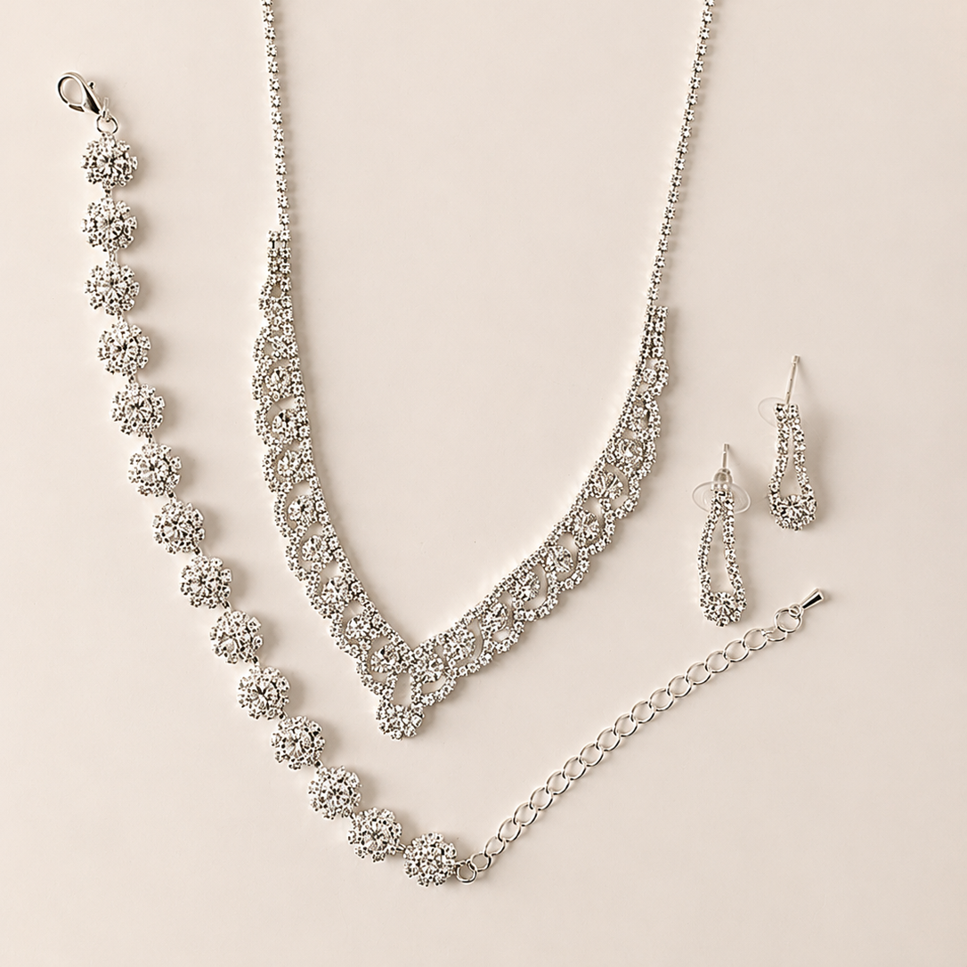Silver jewelry set with necklace, bracelet, and earrings on a beige background