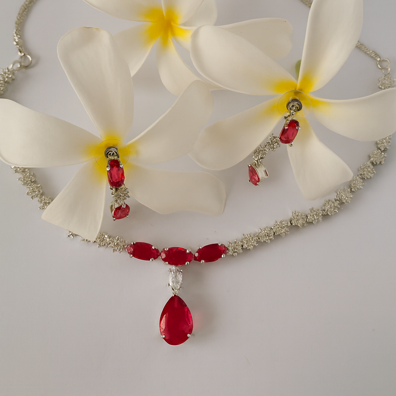 Necklace with red gemstones and white flowers on a gray background