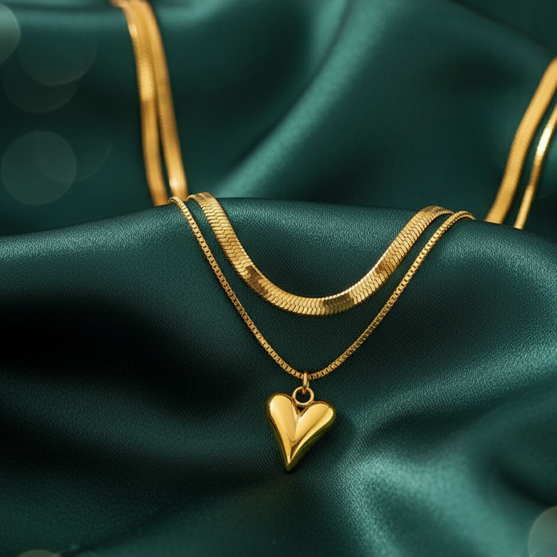 Gold tone necklace with a heart pendant on green satin fabric