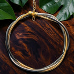 Gold and silver necklace on a wooden surface with green leaves
