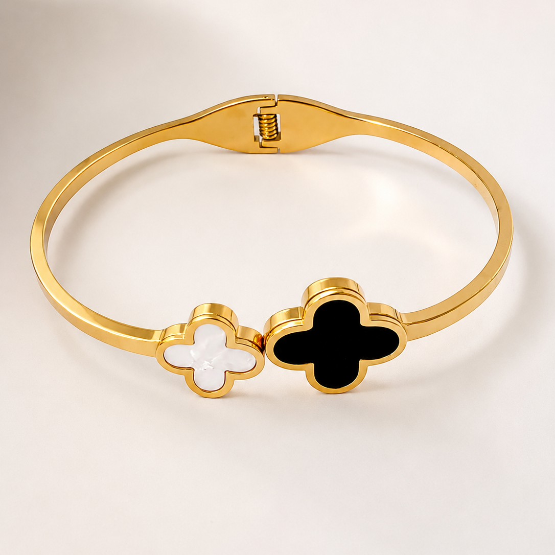 Gold tone bracelet with clover-shaped charms on a light background