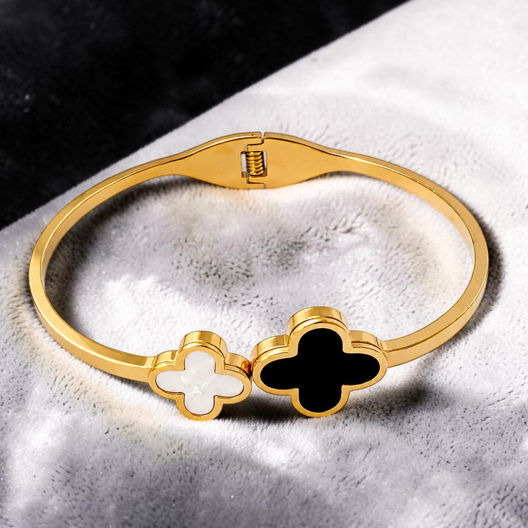 Gold tone bracelet with clover-shaped charms on a textured surface