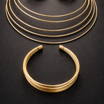 Gold tone bracelets stacked on a dark surface