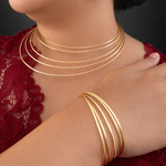 Gold tone necklaces and bracelet on a person wearing a red lace garment.