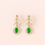 Pair of earrings with green gemstones on a light pink background