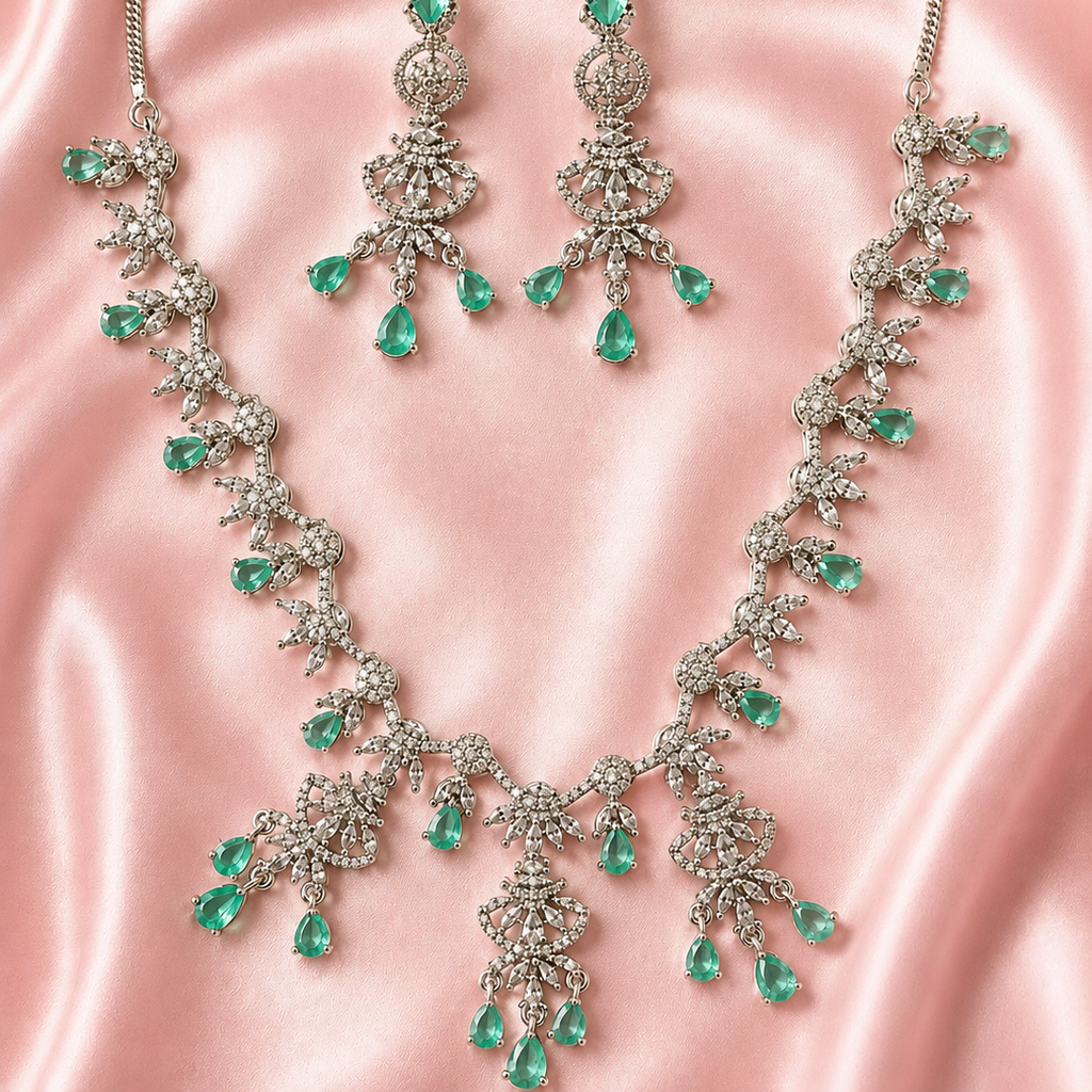 Jewelry set with necklace and earrings featuring green gemstones on a pink satin background
