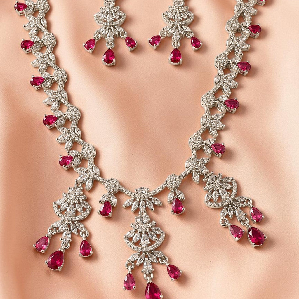 Jewelry set with necklace and earrings featuring red gemstones on a neutral background
