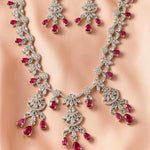 Jewelry set with necklace and earrings featuring red gemstones on a neutral background