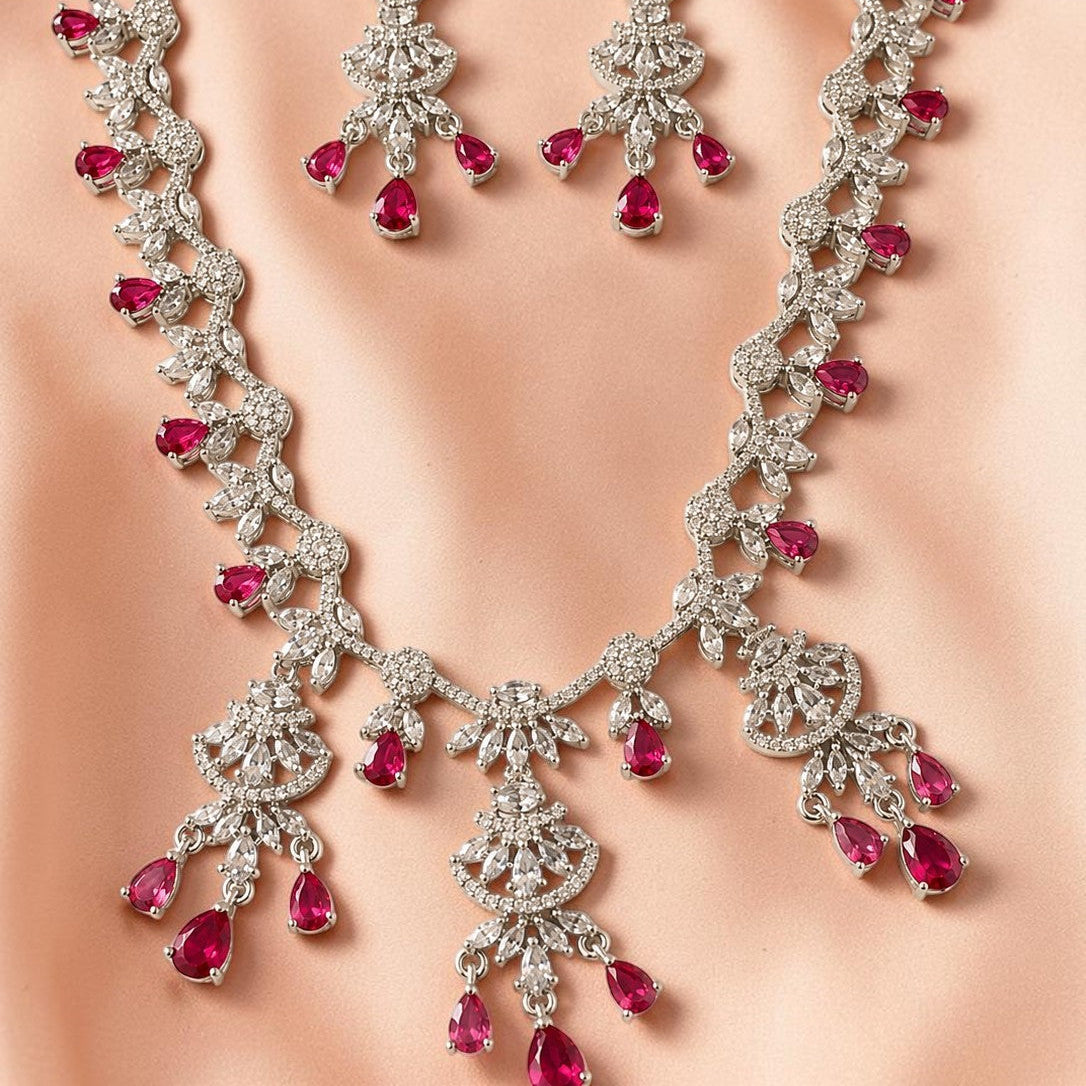 Jewelry set with necklace and earrings featuring red gemstones on a neutral background
