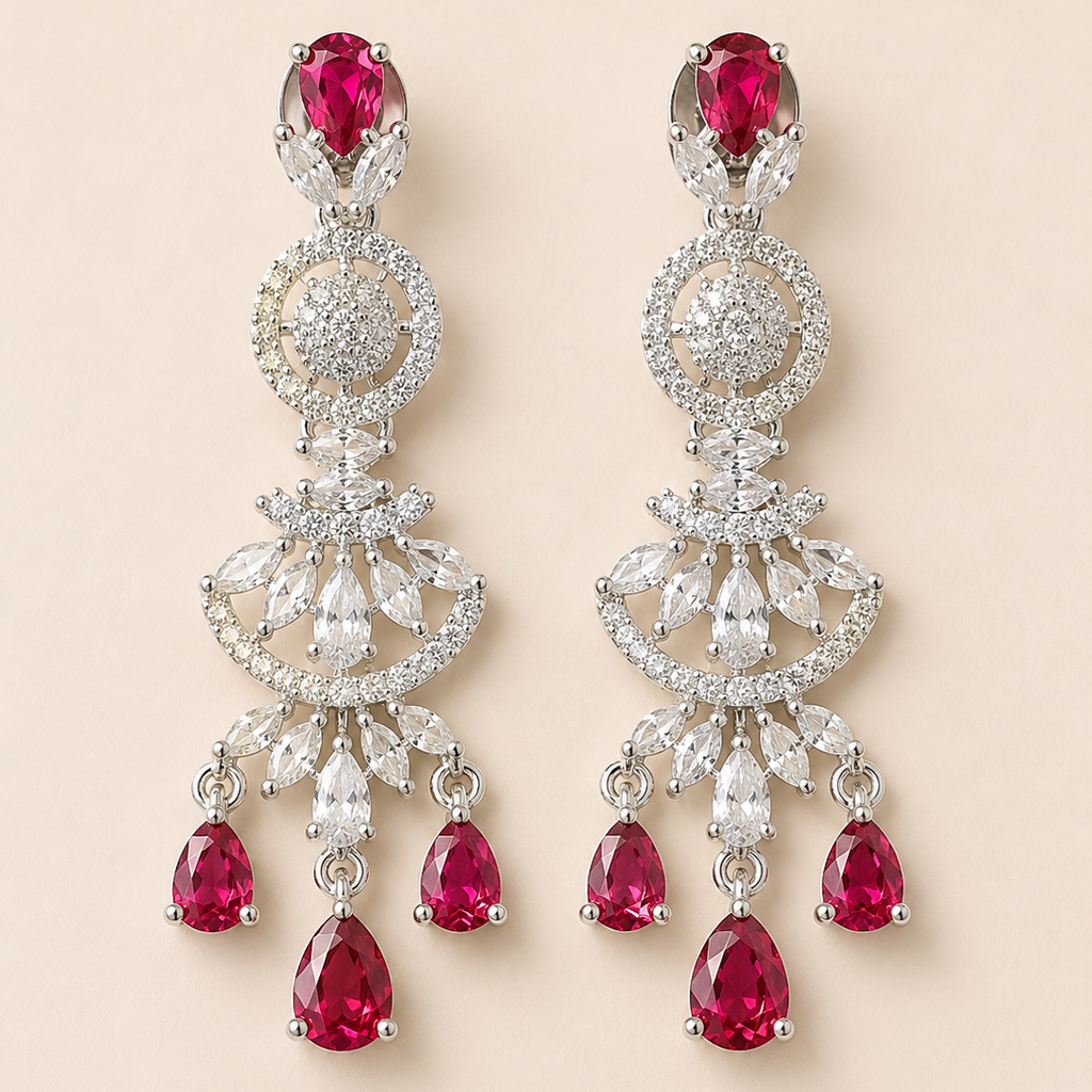 Pair of elegant earrings with red gemstones and intricate silver designs on a beige background